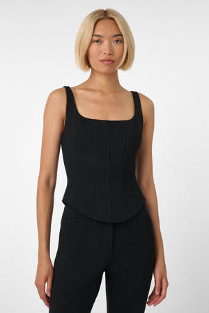 Woman wearing a black sleeveless top and pants on a white background