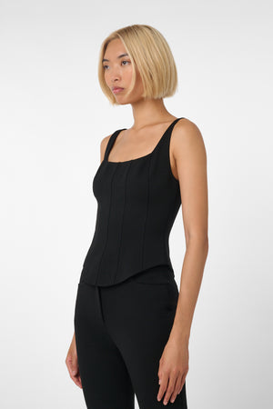 Woman wearing a black sleeveless top and black pants on a white background