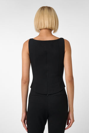 Person wearing a black sleeveless top and black pants on a white background
