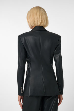 Woman wearing a black vegan leather suit on a light grey background
