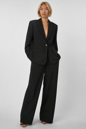 Woman wearing a black oversized suit on a plain background