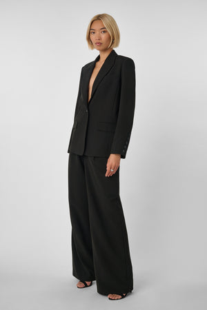 Woman wearing a black oversized suit on a light gray background