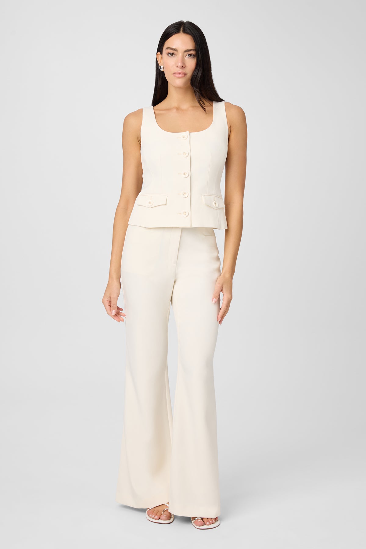 Woman wearing a white sleeveless top and wide-leg pants on a light gray background